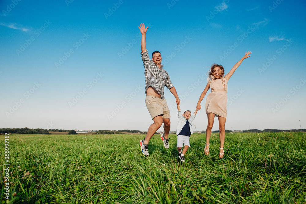 Happy family jumping together in the field in sunny day Happy family jumping together in the field in sunny day