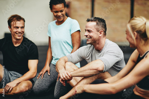 Diverse friends laughing on a gym floor after working out photo