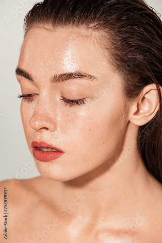 beautiful girl with coral lips and wet skin posing isolated on grey
