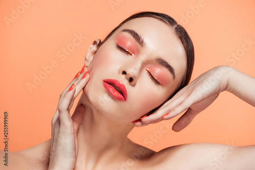 Fotografie beautiful stylish young woman with glitter makeup posing isolated on coral