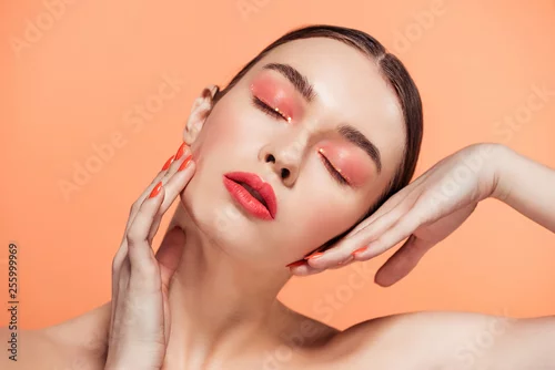 Obraz beautiful stylish young woman with glitter makeup posing isolated on coral