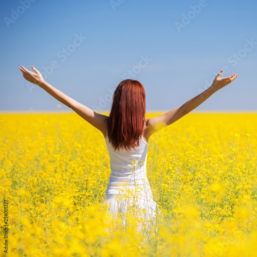 People freedom success concept. Happy woman in the field with flowers at sunny day in the countryside. Nature beauty background, blue sky and yellow flowers. Outdoor lifestyle. © Dmytro Sunagatov