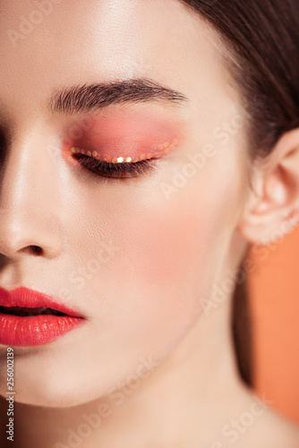 selective focus of beautiful stylish young woman posing isolated on coral