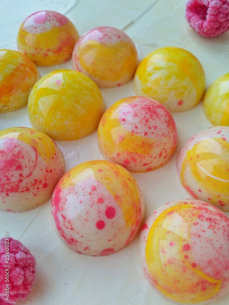 Sweets made of white chocolate in the form of hemispheres of bright color on a light background close-up Sweets made of white chocolate in the form of hemispheres of bright color on a light background close-up