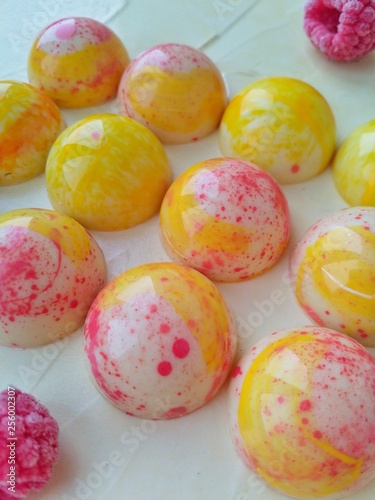 Sweets made of white chocolate in the form of hemispheres of bright color on a light background close-up