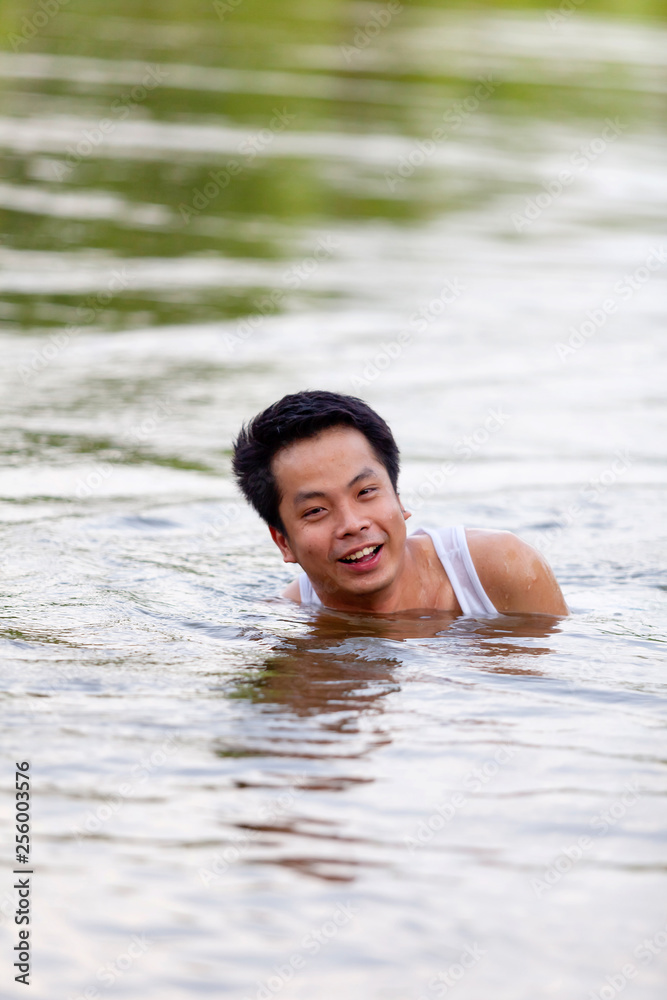 Fototapeta premium A Thai man in white tank top swimming in river