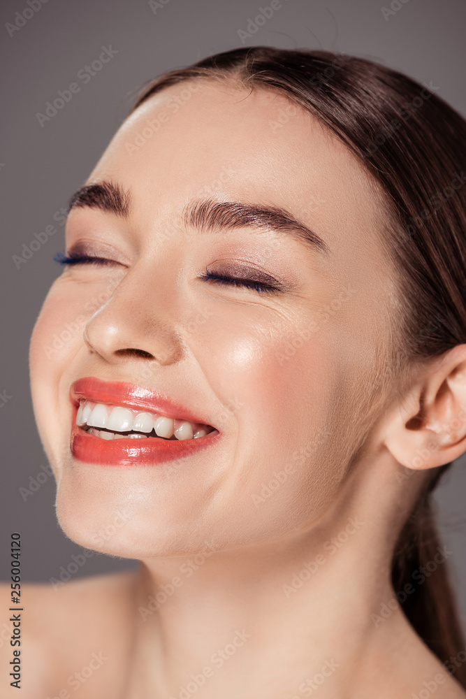 Obraz premium portrait of beautiful smiling girl with eyes closed isolated on grey