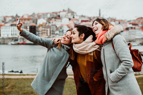 .Three beautiful and funny women traveling together in Porto, Portugal. Taking photos as memories of their trip, carefree and relaxed. Lifestyle. Travel photography