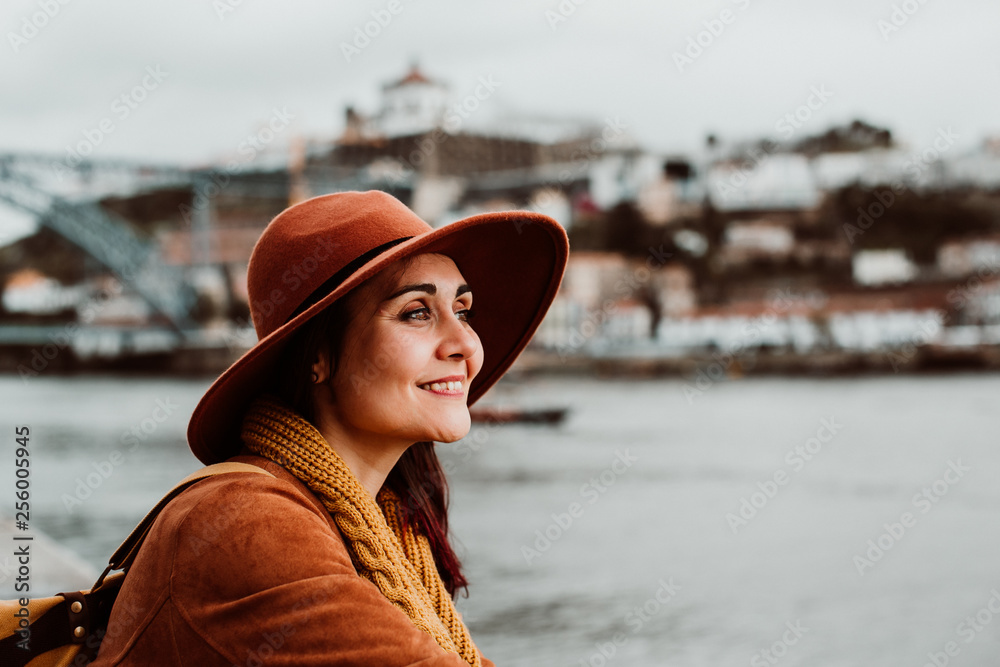 .Young and pretty woman sightseeing in the city of Porto, Portugal. Sitting on the river side, enjoying a beautiful landscape on a windy spring day. Lifestyle. .Young and pretty woman sightseeing in the city of Porto, Portugal. Sitting on the river side, enjoying a beautiful landscape on a windy spring day. Lifestyle.