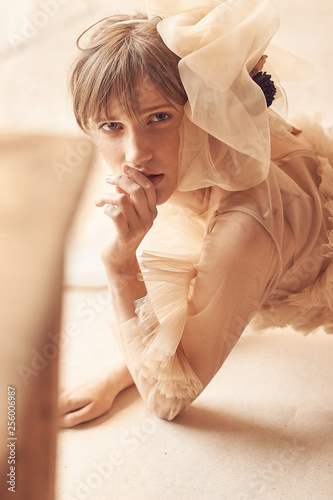 Soft beauty portrait of young dreamy woman with blue eyes and bang, weared in nude tulle dress. Studio shot