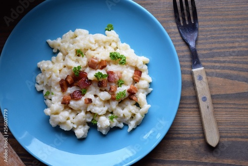 Slovak traditional potato gnocchi with sheep cheese and bacon,wooden table