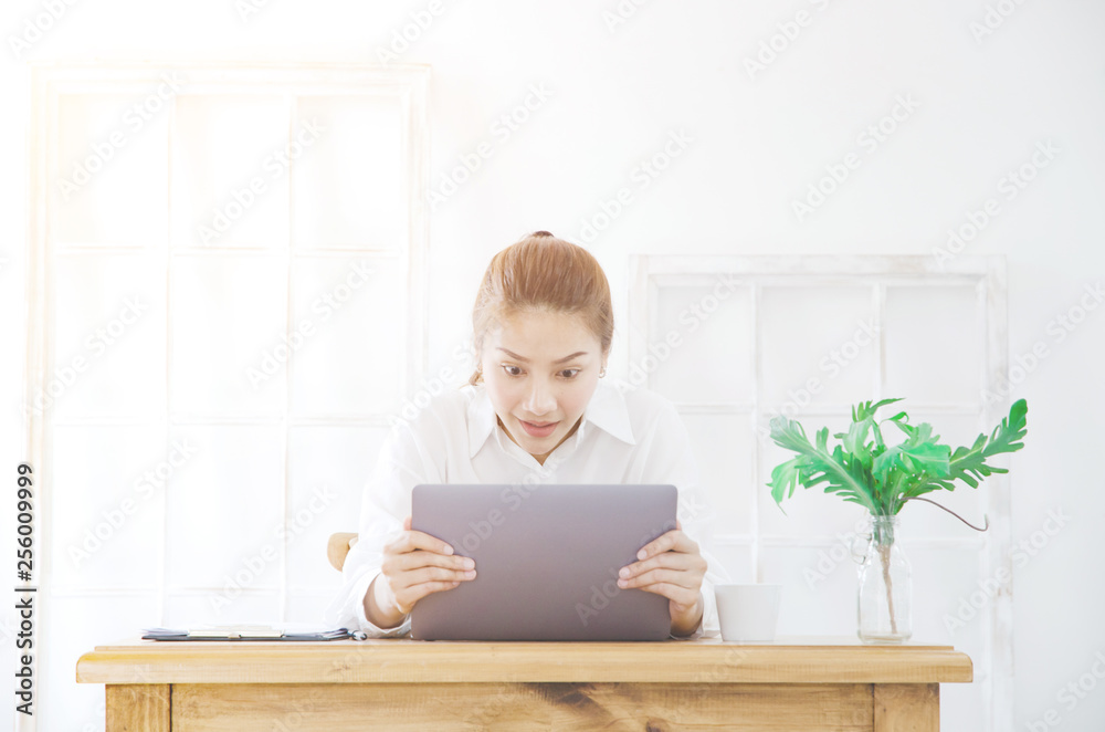 Beautiful Asian woman is smiling.Asian women work with gray laptops on the sofa in the room in the morning. Beautiful Asian woman is smiling.Asian women work with gray laptops on the sofa in the room in the morning.