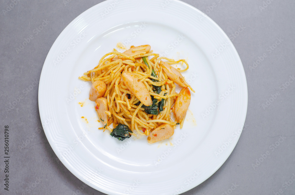 Spaghetti with sausage, Stir-fried sausage, Italian food.Spaghetti with red sauce, white plate on the table in the morning restaurant.