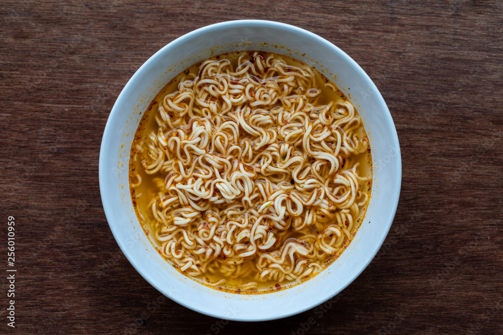 instant noodles is one on a wood brown background with copy space, Quick cooking instant noodles is one on a wood brown background with copy space, Quick cooking