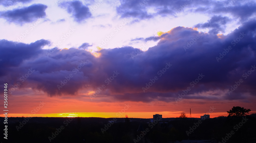 Panorama of a sunrise landscape with colorful clouds over an isolated tree. Orange and yellow sky over the countryside at dawn