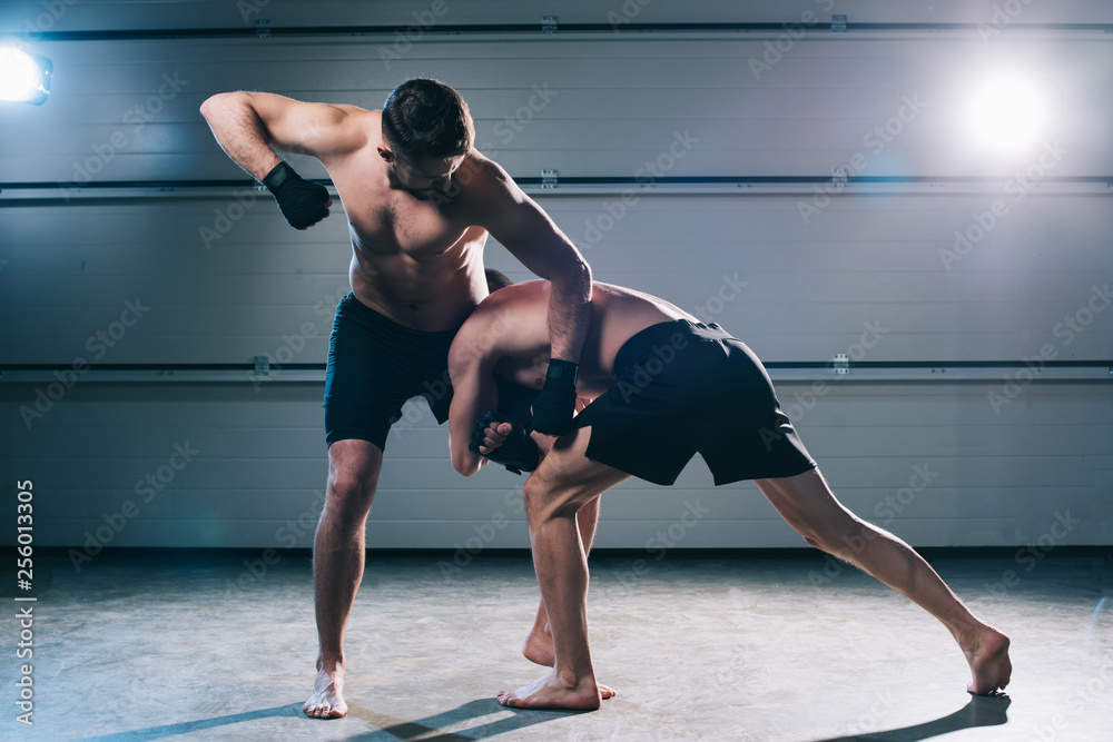 Obraz premium strong muscular shirtless mma fighter punching another while man doing clinch