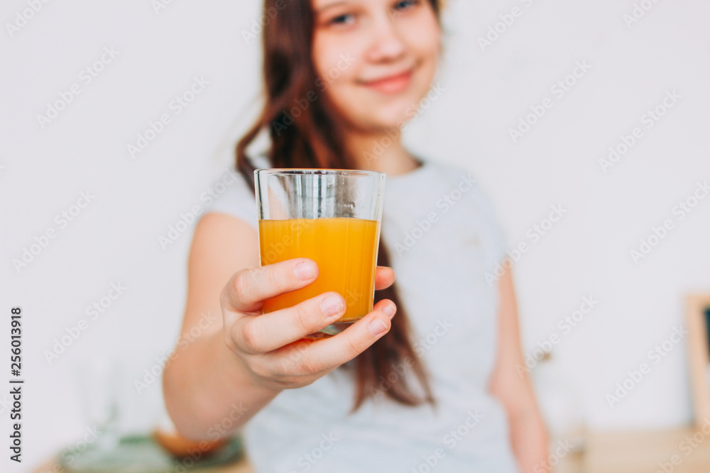 The girl holding glass of orange juice in hand, selective focus The girl holding glass of orange juice in hand, selective focus
