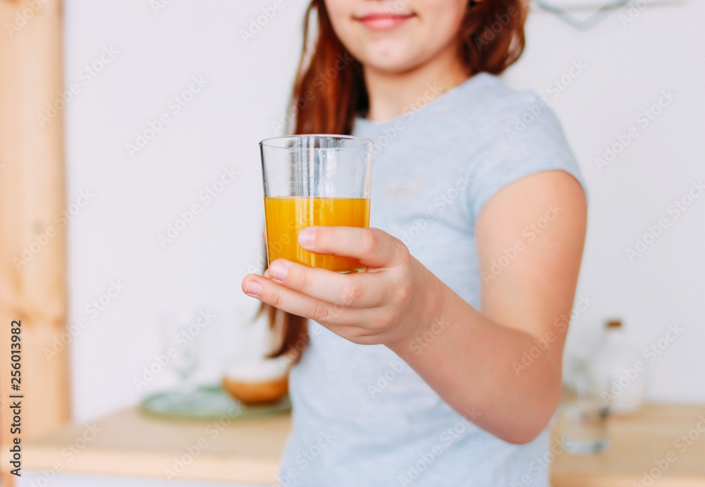 The girl holding glass of orange juice in hand, selective focus The girl holding glass of orange juice in hand, selective focus