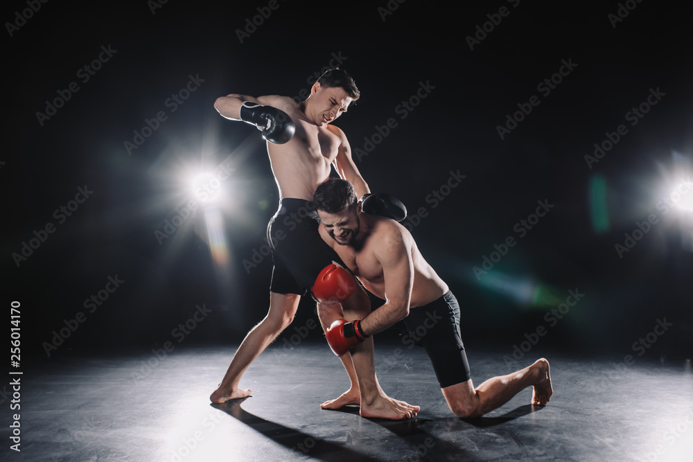 barefoot strong muscular mma fighter in boxing gloves clinching another