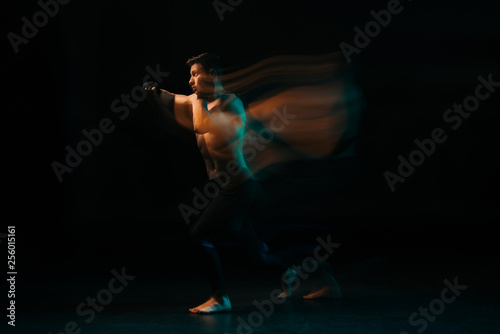 long exposure of orange and green light and shirtless muscular mma fighter doing punch