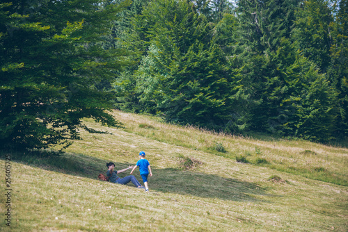 woman resting in shadow in carpathian forest. little boy run to her © phpetrunina14