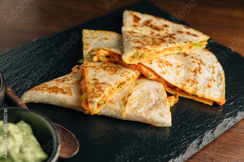 Close up Baked Chicken and Cheese Quesadillas served with Salsa and Guacamole on stone plate. photo