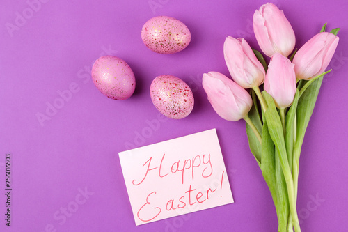 Easter. pink easter eggs and flowers tulips on a trendy purple background. Happy easter. holidays. top view.