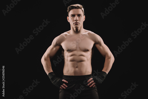strong muscular sportsman looking at camera with hands on hips isolated on black © LIGHTFIELD STUDIOS