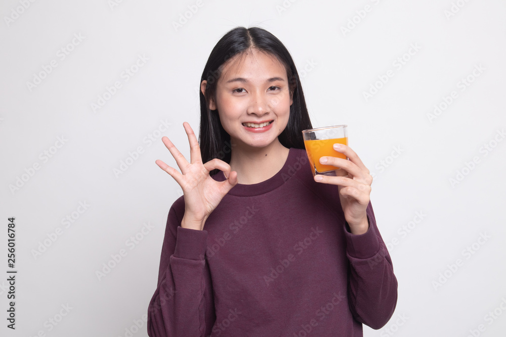 Young Asian woman drink orange juice show OK sign. Young Asian woman drink orange juice show OK sign.