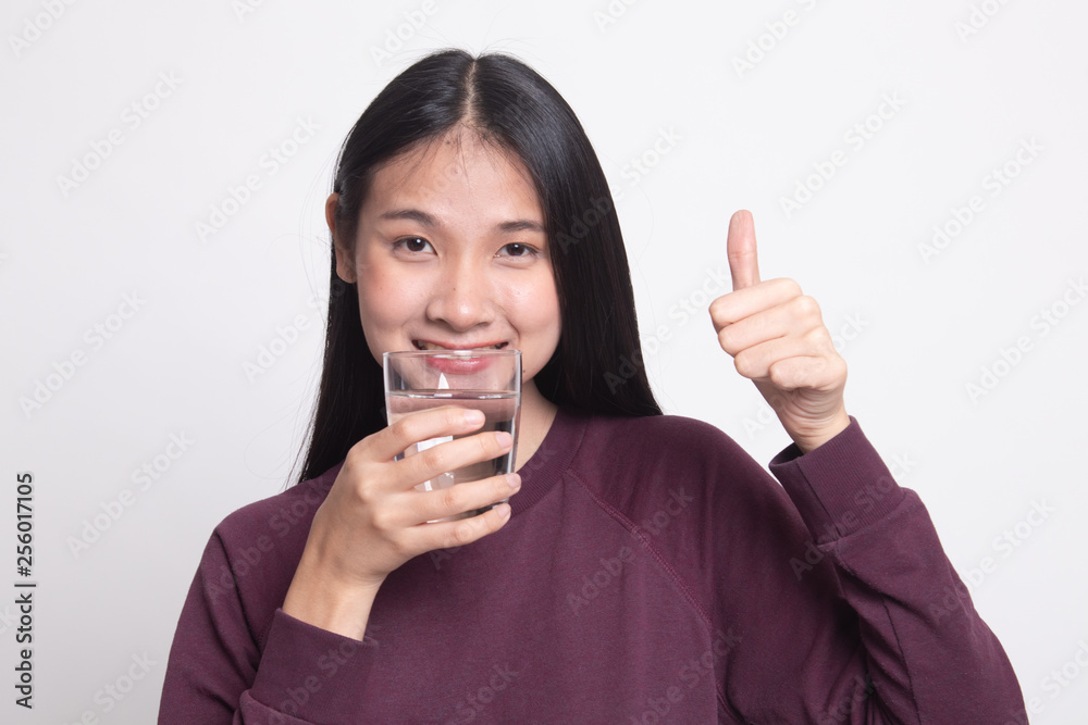 Young Asian woman thumbs up with a glass of drinking water. Young Asian woman thumbs up with a glass of drinking water.