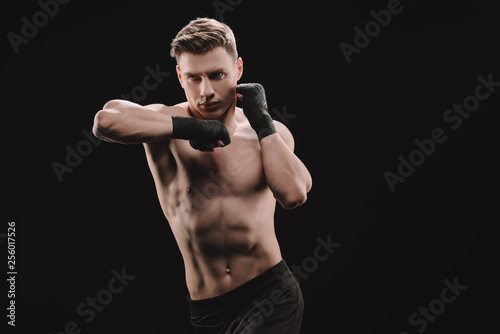 athletic muscular sportsman in bandages doing punch with elbow isolated on black