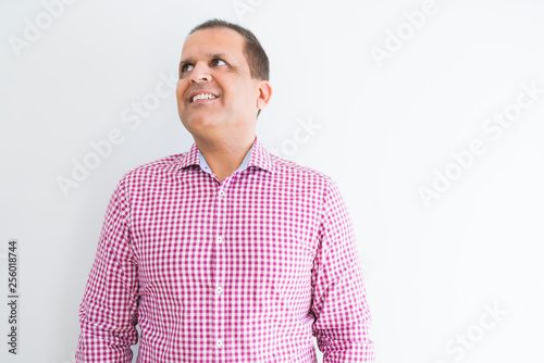 Middle age man wearing business shirt over white wall smiling looking side and staring away thinking.