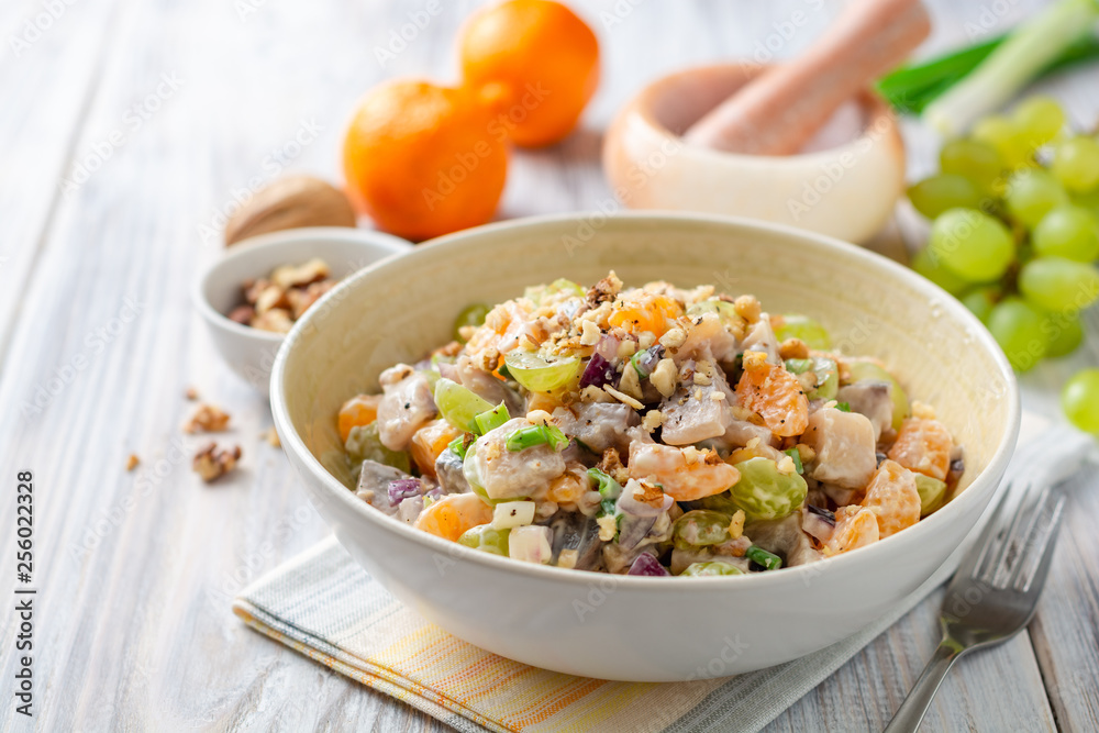 Salad with herring, tangerines, grapes, onions and walnuts in bowl on wooden table. Selective focus. Salad with herring, tangerines, grapes, onions and walnuts in bowl on wooden table. Selective focus.