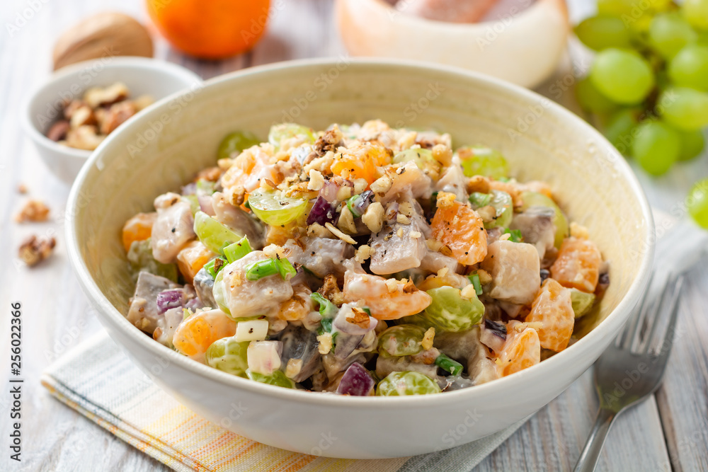 Salad with herring, tangerines, grapes, onions and walnuts in bowl on wooden table. Selective focus. Salad with herring, tangerines, grapes, onions and walnuts in bowl on wooden table. Selective focus.
