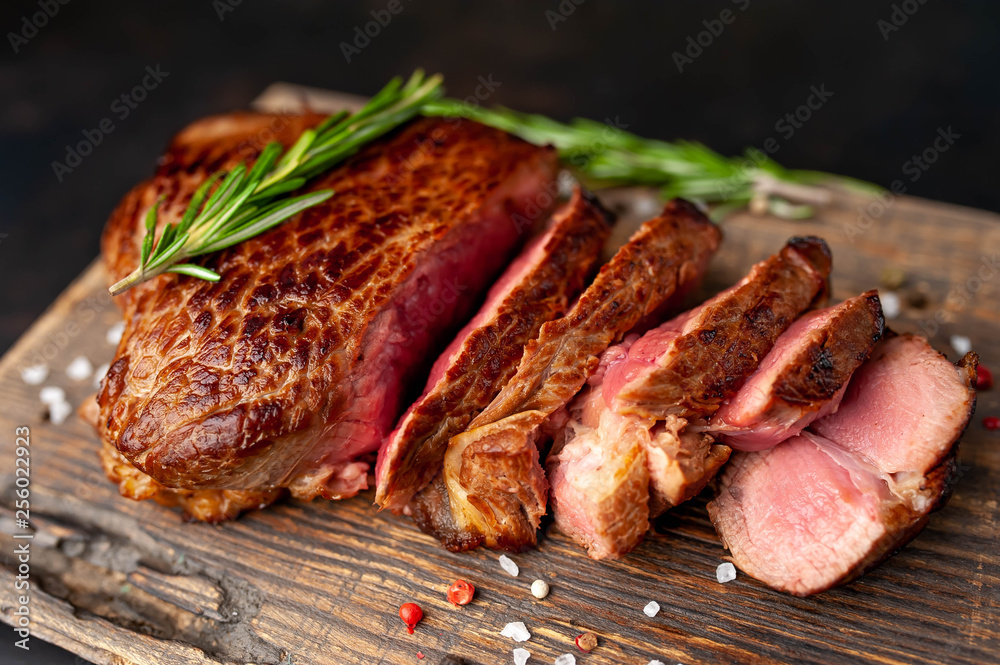 Beef steak, herbs and spices on a cutting board against a background of stone