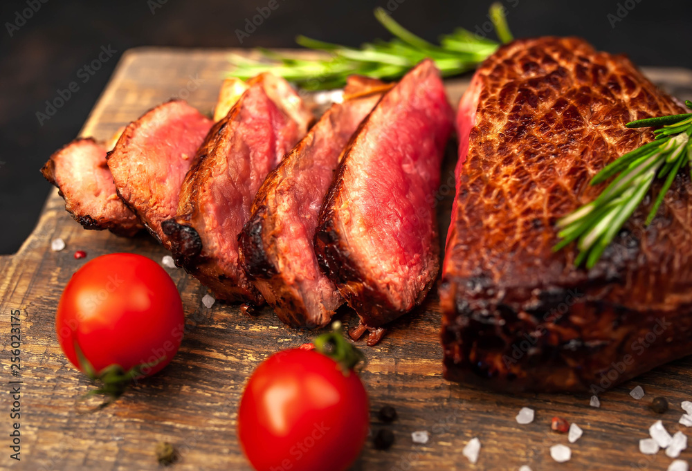 Beef steak, herbs and spices on a cutting board against a background of stone Beef steak, herbs and spices on a cutting board against a background of stone
