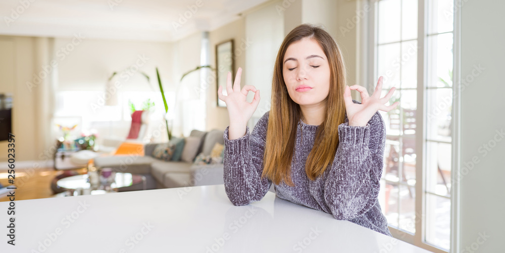 Beautiful young woman at home relax and smiling with eyes closed doing meditation gesture with fingers. Yoga concept.