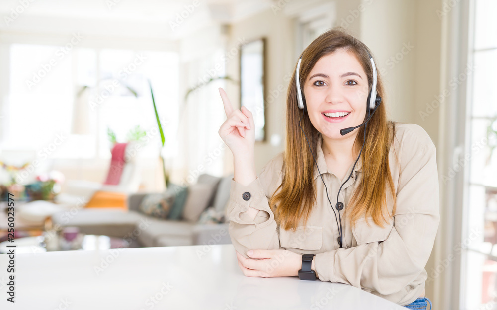 Beautiful young operator woman wearing headset at the office with a big smile on face, pointing with hand and finger to the side looking at the camera. Beautiful young operator woman wearing headset at the office with a big smile on face, pointing with hand and finger to the side looking at the camera.