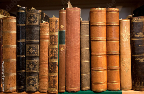 Vintage bookshelf with many books in leather covers, printed at 19th century and before. Knowledge background of library or bookstore