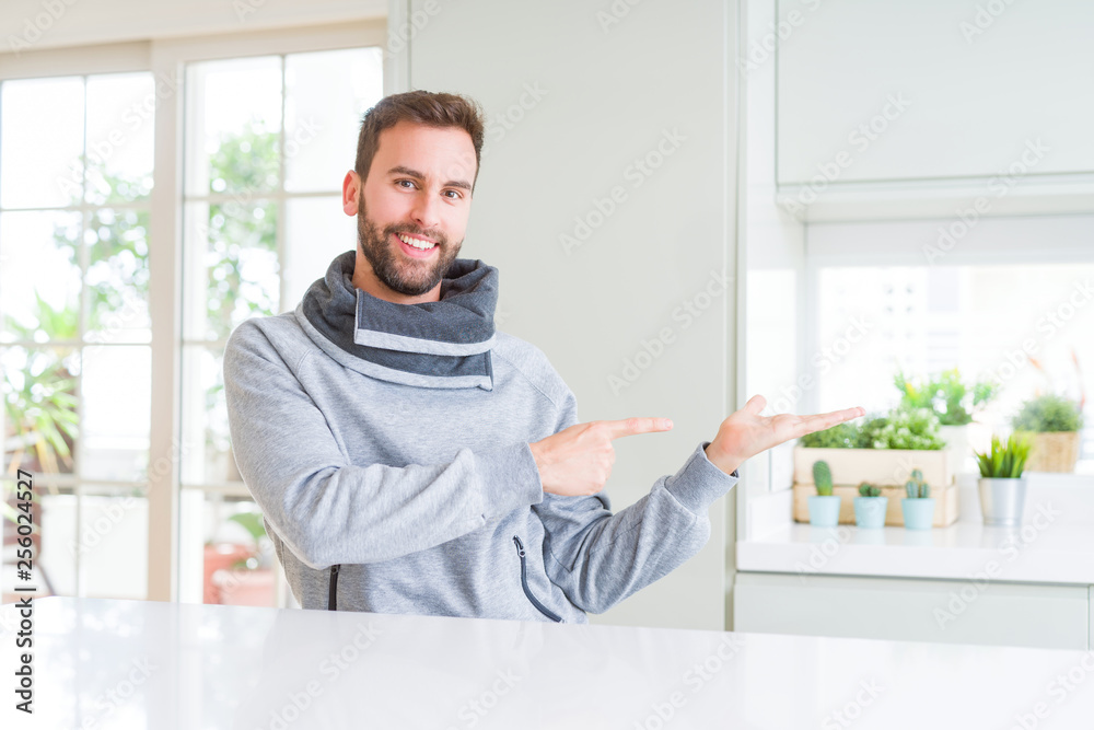 Handsome man at home amazed and smiling to the camera while presenting with hand and pointing with finger. Handsome man at home amazed and smiling to the camera while presenting with hand and pointing with finger.