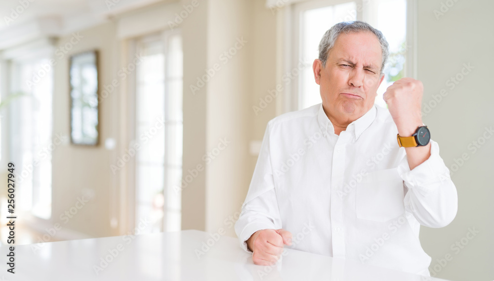 Handsome senior man at home angry and mad raising fist frustrated and furious while shouting with anger. Rage and aggressive concept. Handsome senior man at home angry and mad raising fist frustrated and furious while shouting with anger. Rage and aggressive concept.