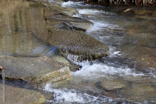 The water flowing over the big rocks in the creek.