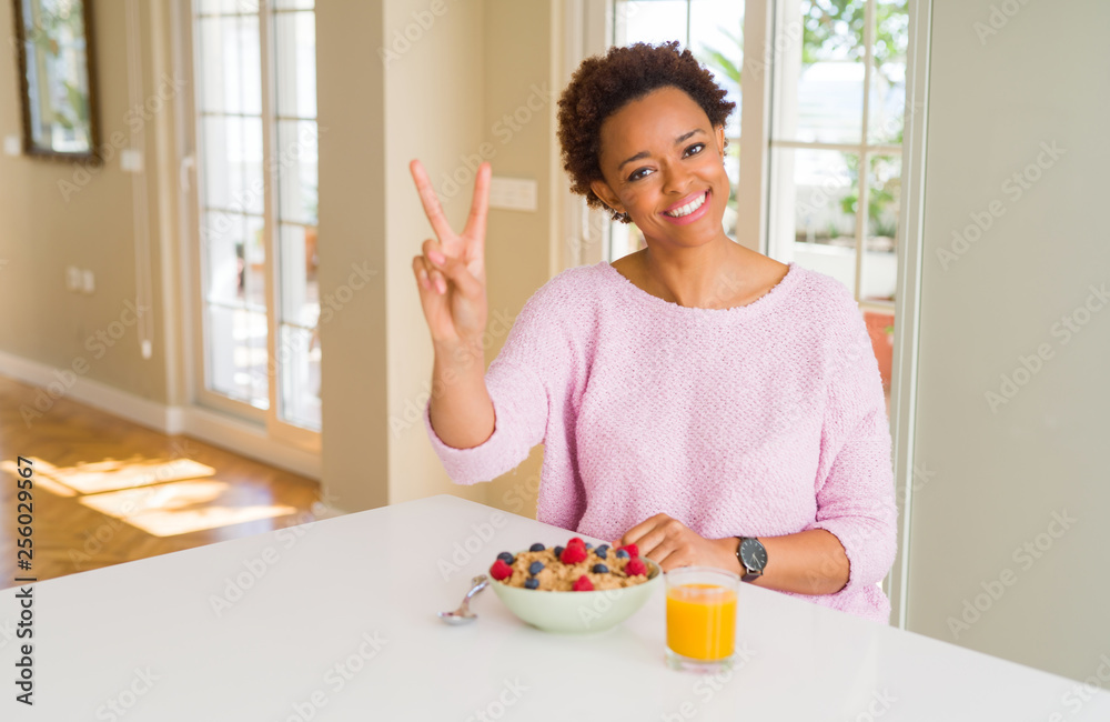 Young african american woman having healthy breakfast in the morning at home smiling looking to the camera showing fingers doing victory sign. Number two. Young african american woman having healthy breakfast in the morning at home smiling looking to the camera showing fingers doing victory sign. Number two.