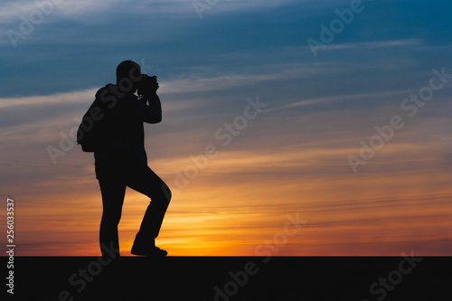 silhouette of photographer taking picture of landscape during sunset