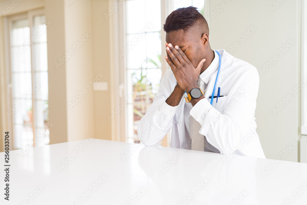 Fototapeta premium African american doctor man at the clinic with sad expression covering face with hands while crying. Depression concept.