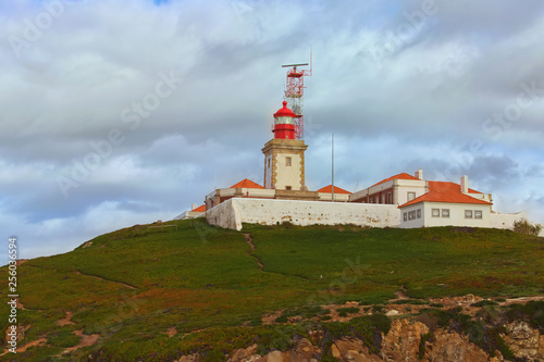 Scenic landscape view of lighthouse on the hill at the Cabo da Roca (Cape Roca). It is a cape which forms the westernmost extent of mainland Portugal, continental Europe and the Eurasian land mass © evgenij84