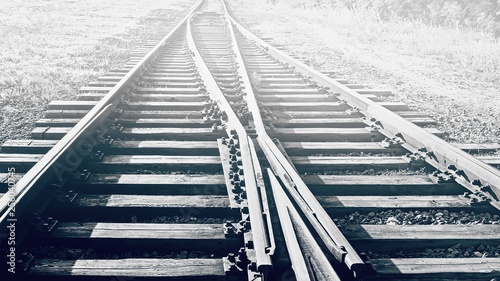 A railway track litted by the sun, black and white.