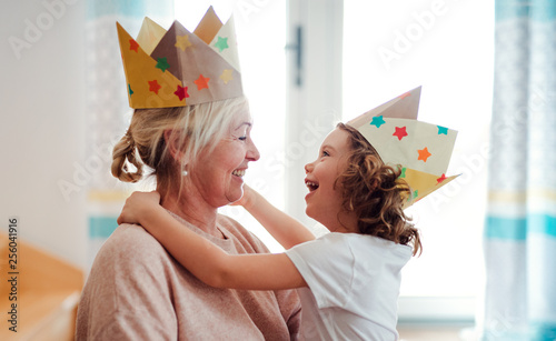 A portrait of small girl with grandmother having fun at home. photo