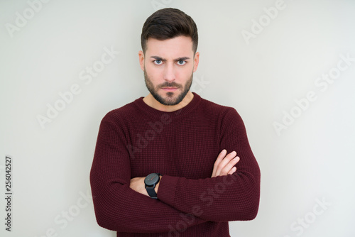 Young handsome man wearing a sweater over isolated background skeptic and nervous, disapproving expression on face with crossed arms. Negative person. © Krakenimages.com