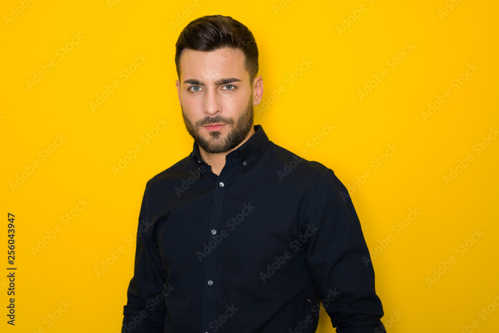 Handsome young hispanic man posing as model over isolated yellow background Handsome young hispanic man posing as model over isolated yellow background